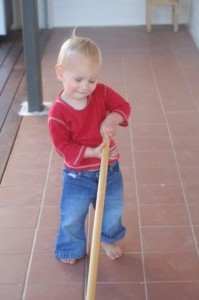 little boy using broom as cane